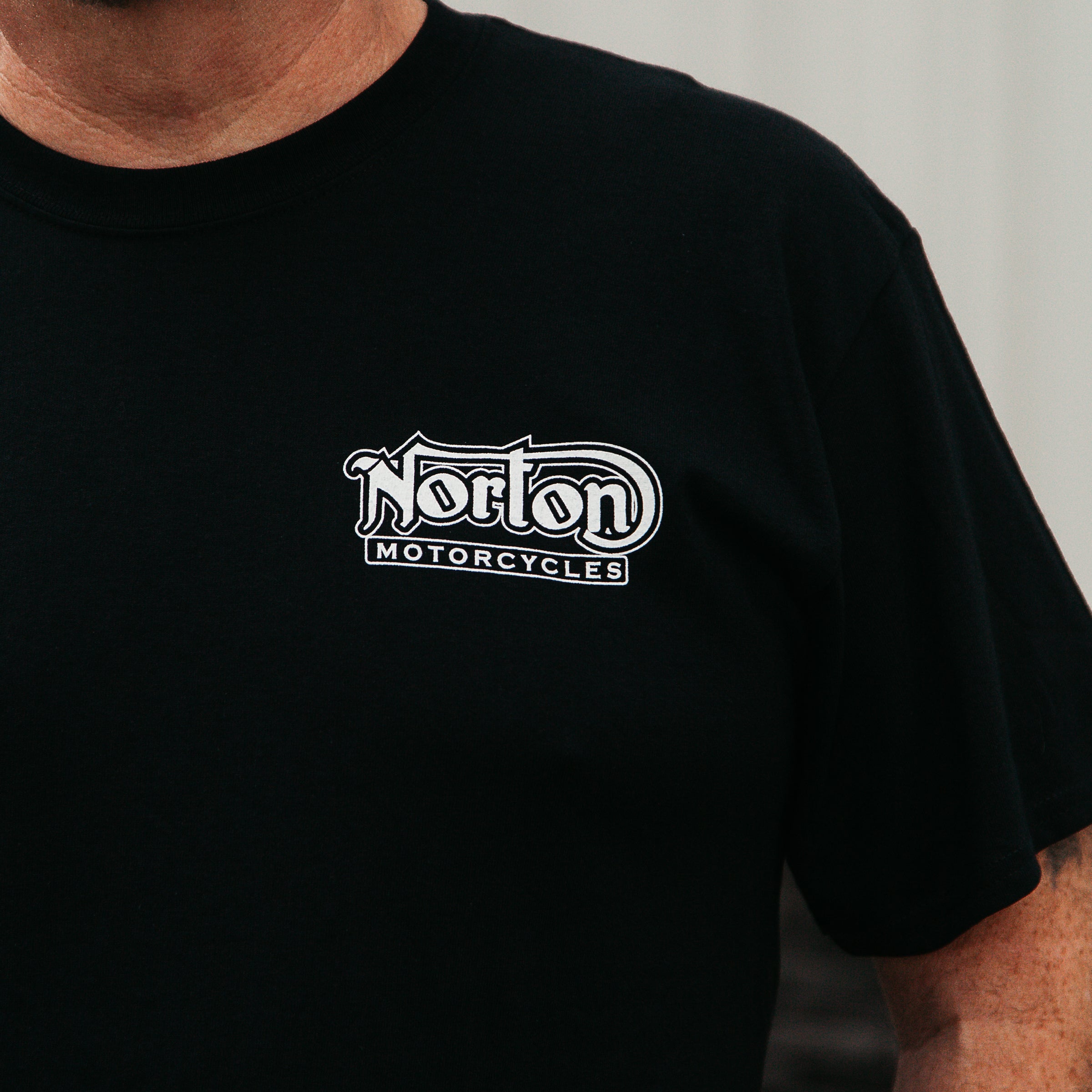 Dreamcycle Motorcycle Museum |  Photo of mans shoulder wearing a black shirt with the text "Norton motorcycles|