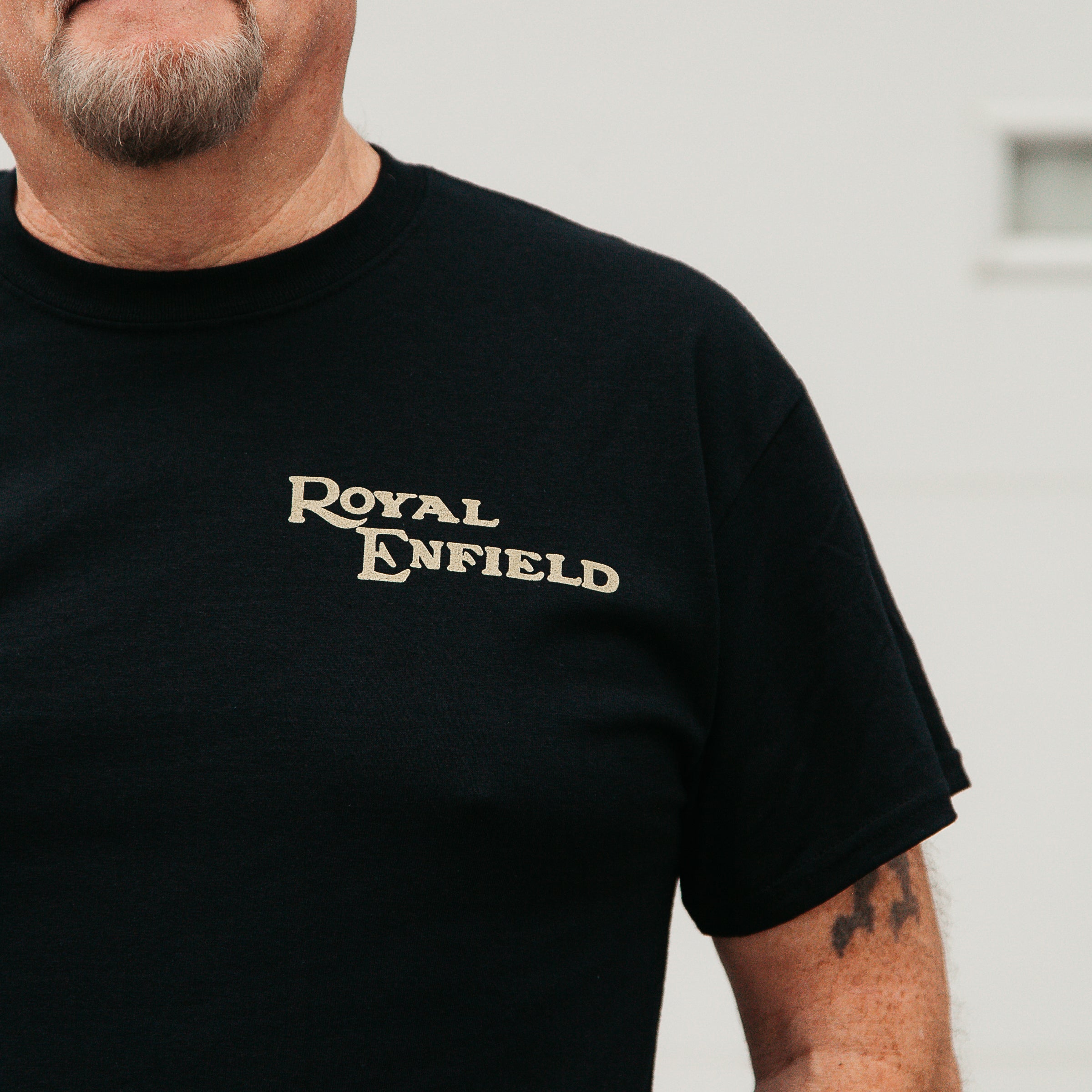 Dreamcycle Motorcycle Museum |  Mans shoulder wearing black shirt with text "Royal Enfield" in lifestyle setting .